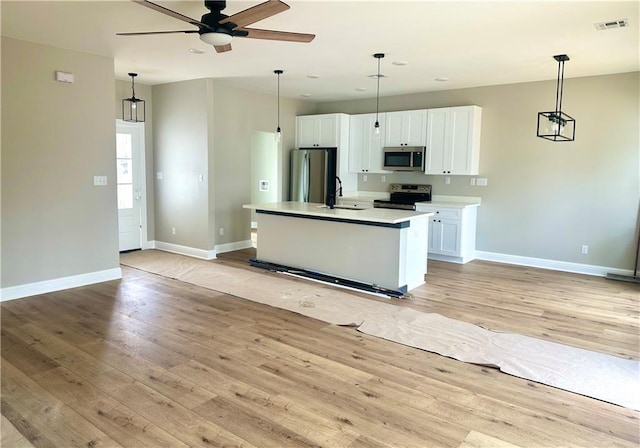 kitchen with stainless steel appliances, light wood-type flooring, a sink, and white cabinetry