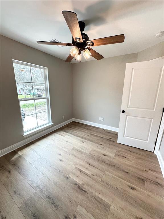 unfurnished room featuring ceiling fan, baseboards, and wood finished floors