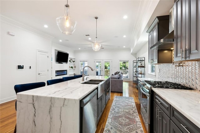 kitchen with crown molding, open floor plan, appliances with stainless steel finishes, french doors, and a glass covered fireplace