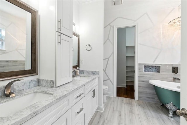 full bathroom featuring double vanity, a soaking tub, toilet, and a sink