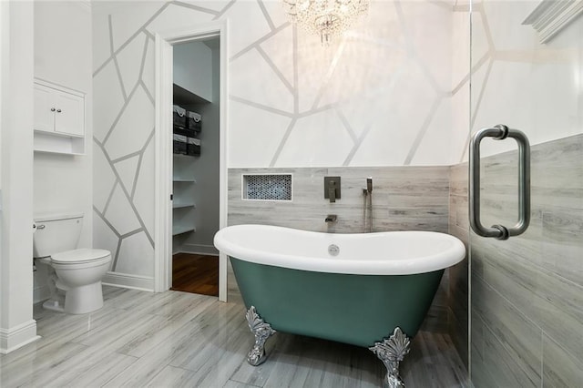 bathroom featuring a soaking tub, toilet, tile walls, and wood finished floors