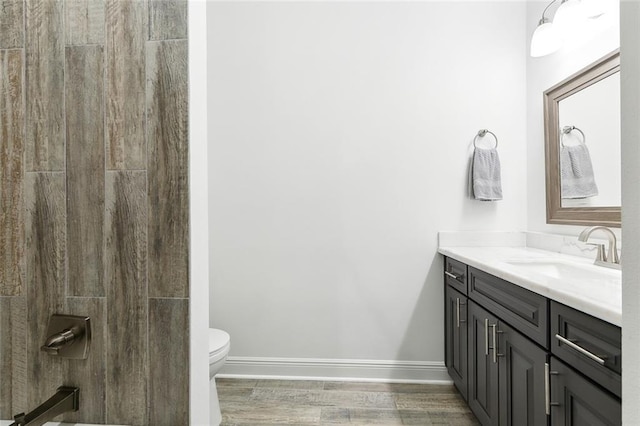 bathroom featuring vanity, toilet, wood finished floors, and baseboards