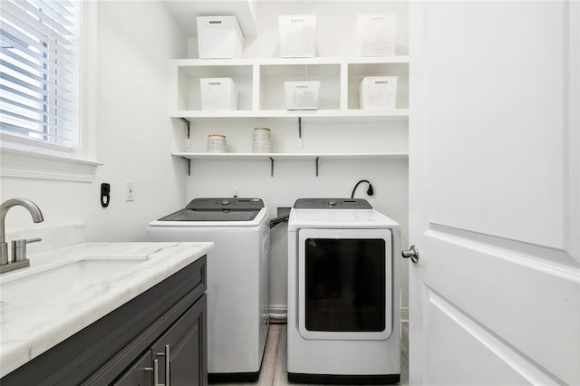 laundry room featuring a sink, light wood-type flooring, cabinet space, and separate washer and dryer