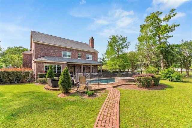 rear view of house featuring a fenced in pool, a patio, a lawn, a chimney, and brick siding