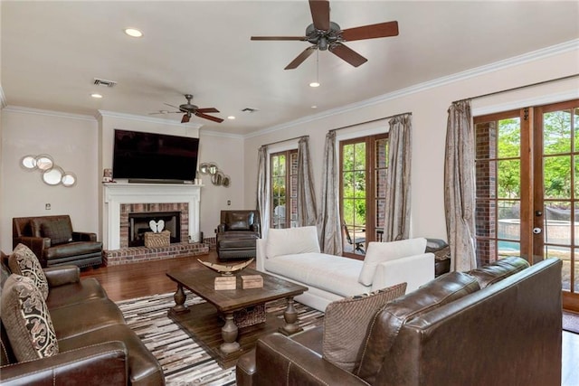 living room with a healthy amount of sunlight, visible vents, a fireplace, and wood finished floors