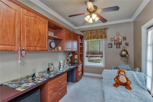 office space with a ceiling fan, light carpet, crown molding, and built in desk