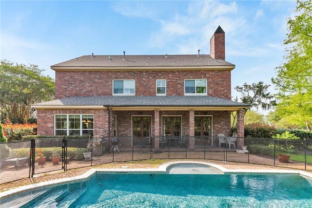 rear view of property with a fenced in pool, brick siding, a chimney, a patio area, and fence