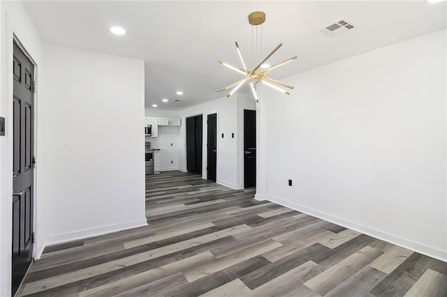 empty room featuring recessed lighting, visible vents, a notable chandelier, and wood finished floors