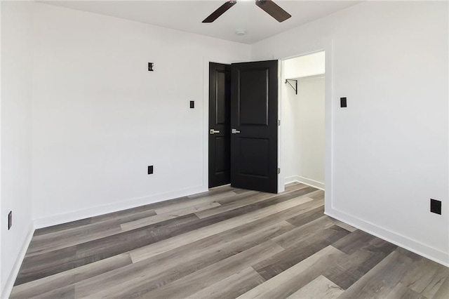 empty room with a ceiling fan, baseboards, and wood finished floors