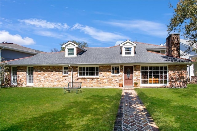 view of front facade featuring brick siding, roof with shingles, and a front yard