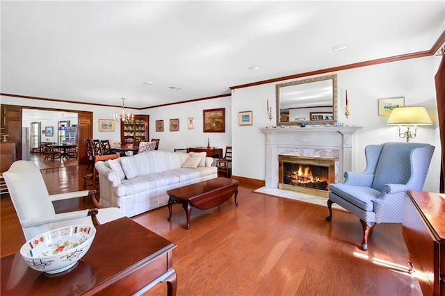 living area featuring a high end fireplace, ornamental molding, baseboards, and wood finished floors