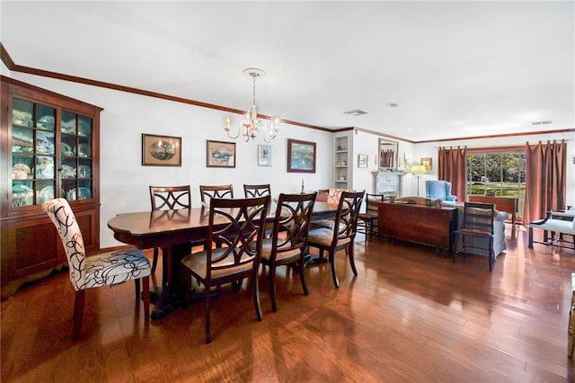 dining space featuring visible vents, a notable chandelier, wood finished floors, and ornamental molding