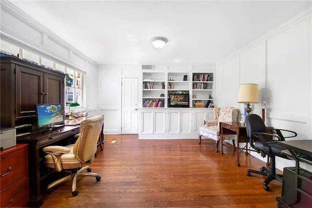 office featuring built in shelves, wood finished floors, ornamental molding, and a decorative wall