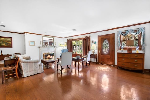 foyer with a glass covered fireplace, visible vents, wood-type flooring, and ornamental molding