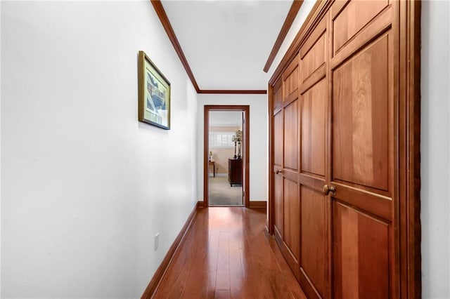 corridor featuring crown molding, baseboards, and dark wood-style flooring