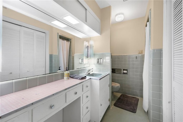 full bath featuring vanity, a wainscoted wall, a closet, tile walls, and toilet