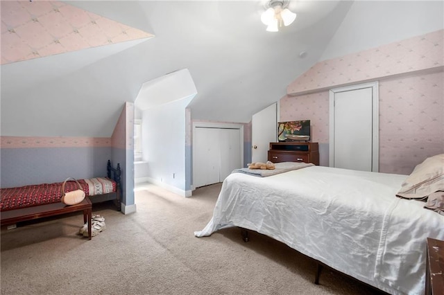 carpeted bedroom with baseboards, multiple closets, vaulted ceiling, and wallpapered walls