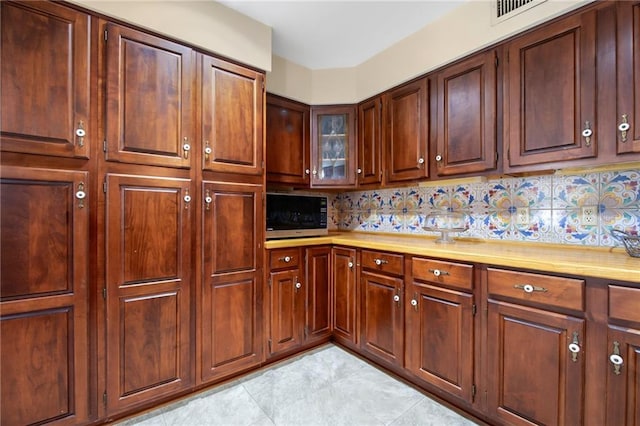 kitchen featuring light tile patterned floors, decorative backsplash, light countertops, and visible vents