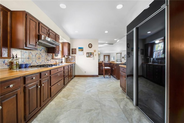 kitchen featuring backsplash, plenty of natural light, under cabinet range hood, and stainless steel gas cooktop