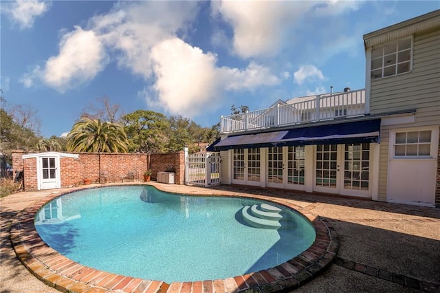 view of swimming pool with a fenced in pool, french doors, and a gate