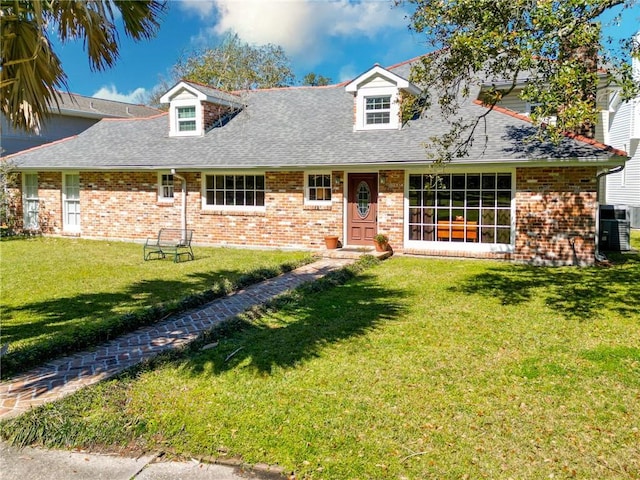 view of front facade with a front yard, brick siding, and roof with shingles