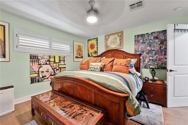 bedroom featuring ceiling fan, wood finished floors, visible vents, and baseboards