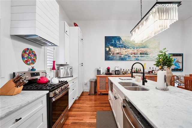 kitchen featuring custom range hood, a sink, wood finished floors, appliances with stainless steel finishes, and white cabinets