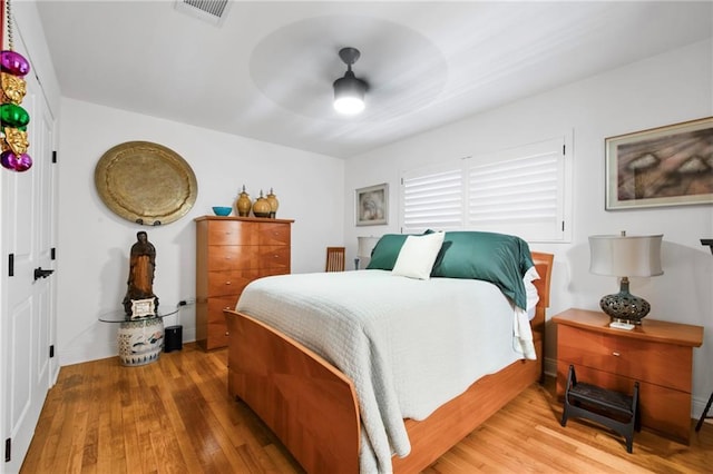 bedroom with a ceiling fan, wood finished floors, and visible vents