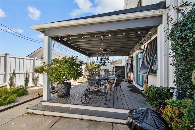 wooden terrace with outdoor dining area, ceiling fan, and fence