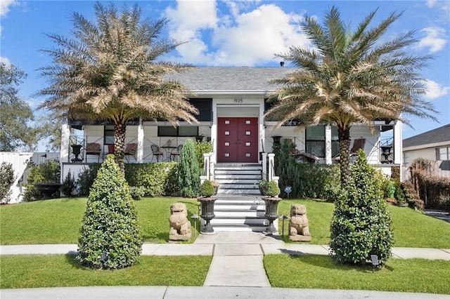 view of front of property featuring a front lawn and roof with shingles