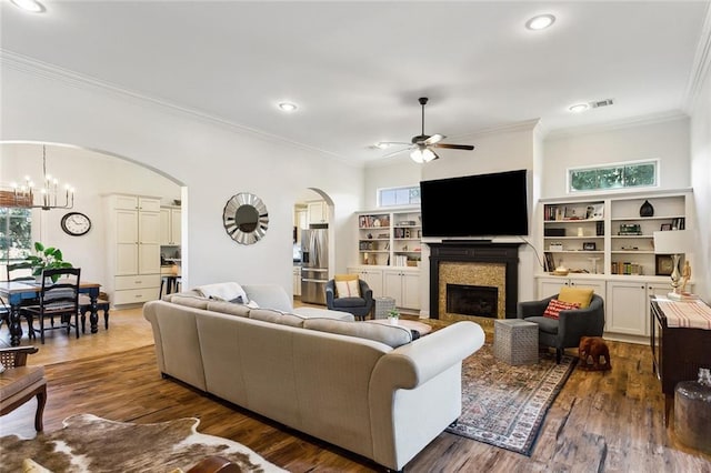 living area with arched walkways, a healthy amount of sunlight, wood finished floors, and a fireplace