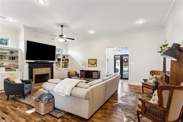 living area with a healthy amount of sunlight, a fireplace, ornamental molding, and wood finished floors