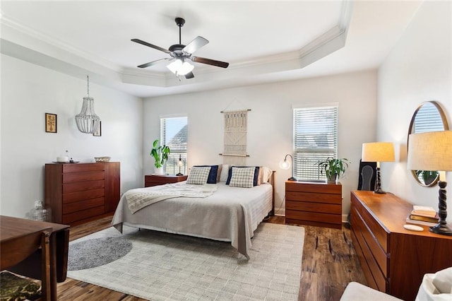 bedroom with crown molding, a raised ceiling, ceiling fan, and wood finished floors