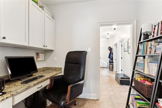 home office with baseboards, light tile patterned flooring, and built in desk