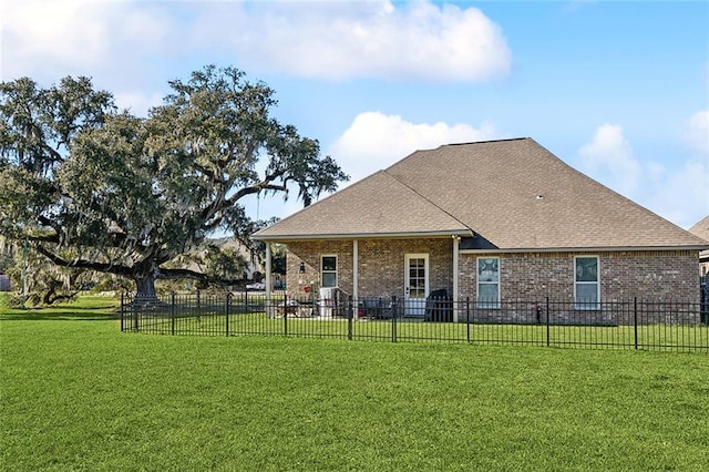 rear view of property featuring a yard, fence, brick siding, and roof with shingles