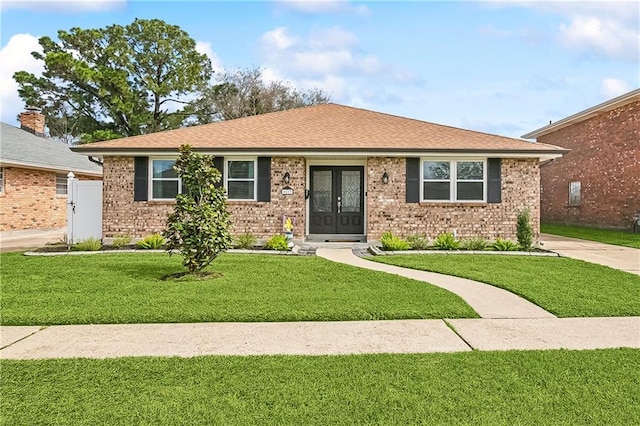 ranch-style home with a front yard, french doors, brick siding, and a shingled roof