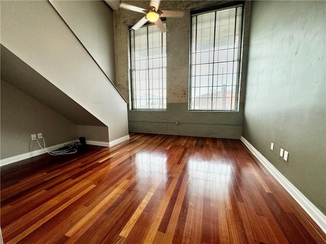 interior space featuring baseboards, wood-type flooring, and a ceiling fan