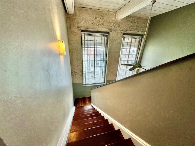 stairway with baseboards, ceiling fan, beamed ceiling, wood ceiling, and wood finished floors