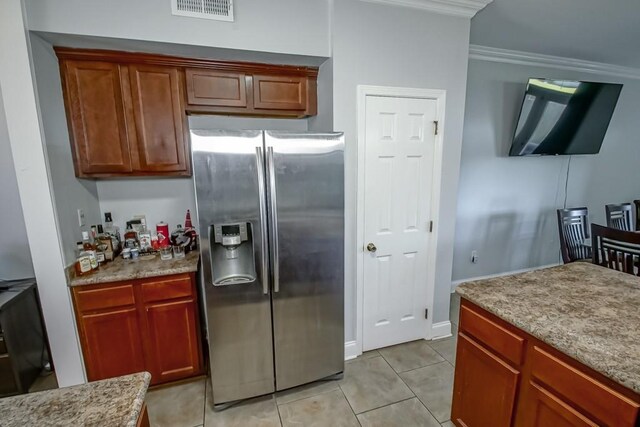 kitchen featuring light tile patterned floors, visible vents, stainless steel fridge, and crown molding