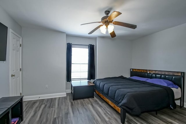 bedroom with dark wood-style floors, ceiling fan, and baseboards