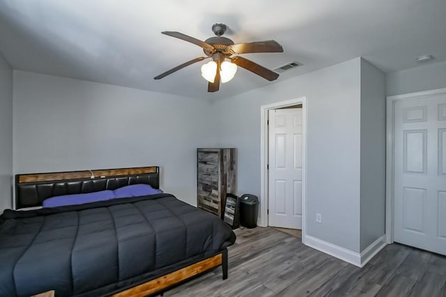 bedroom with visible vents, a ceiling fan, baseboards, and wood finished floors