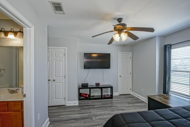 bedroom with baseboards, wood finished floors, visible vents, and a sink