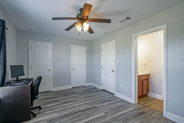 home office featuring a ceiling fan, wood finished floors, visible vents, and baseboards