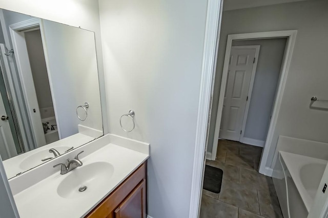 full bathroom with baseboards, tile patterned floors, vanity, and a tub to relax in