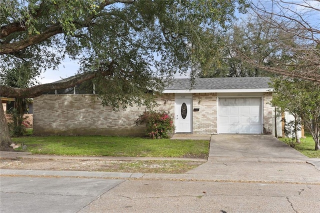 ranch-style home featuring a shingled roof, concrete driveway, a front lawn, a garage, and brick siding