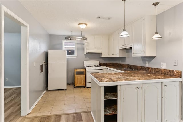 kitchen with white appliances, visible vents, a sink, under cabinet range hood, and dark countertops