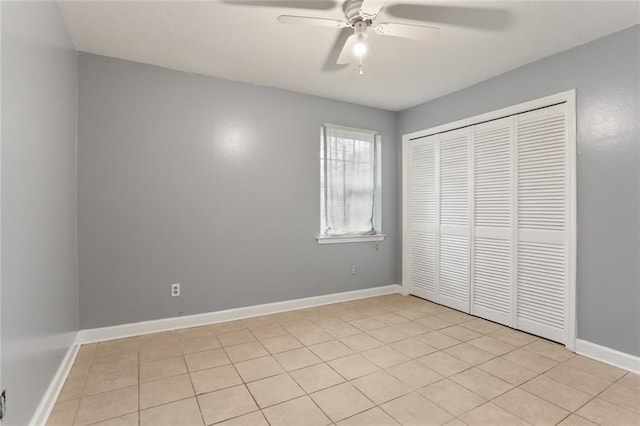 unfurnished bedroom featuring a ceiling fan, light tile patterned floors, baseboards, and a closet