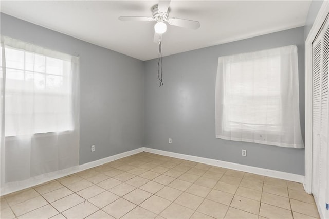 spare room featuring tile patterned floors, baseboards, and a ceiling fan