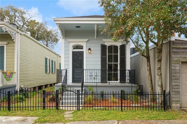 shotgun-style home featuring a fenced front yard, a porch, and a gate