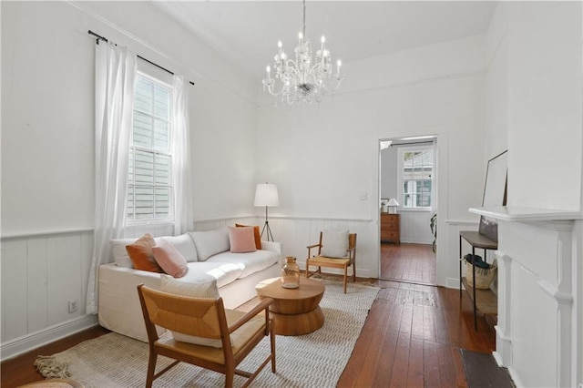 living area featuring a notable chandelier, wainscoting, and hardwood / wood-style floors